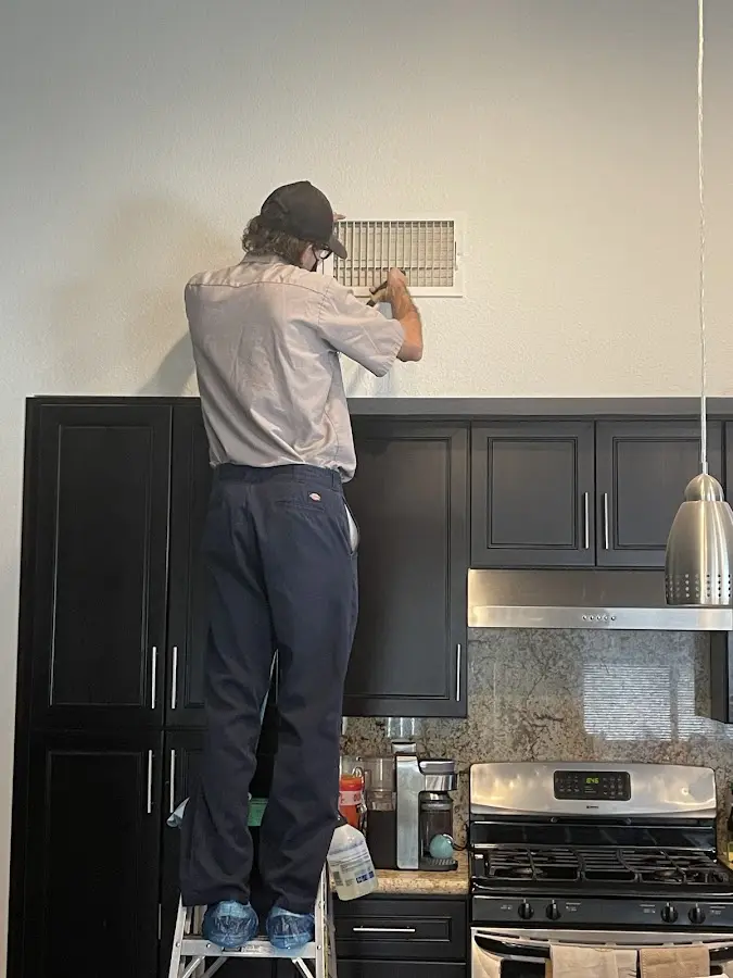 Technician inspecting an air vent during HVAC service in Henrietta